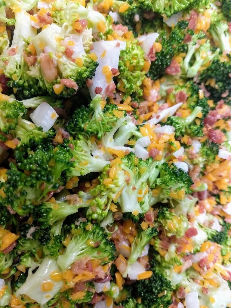 a close up of a broccoli salad with cheese and bacon