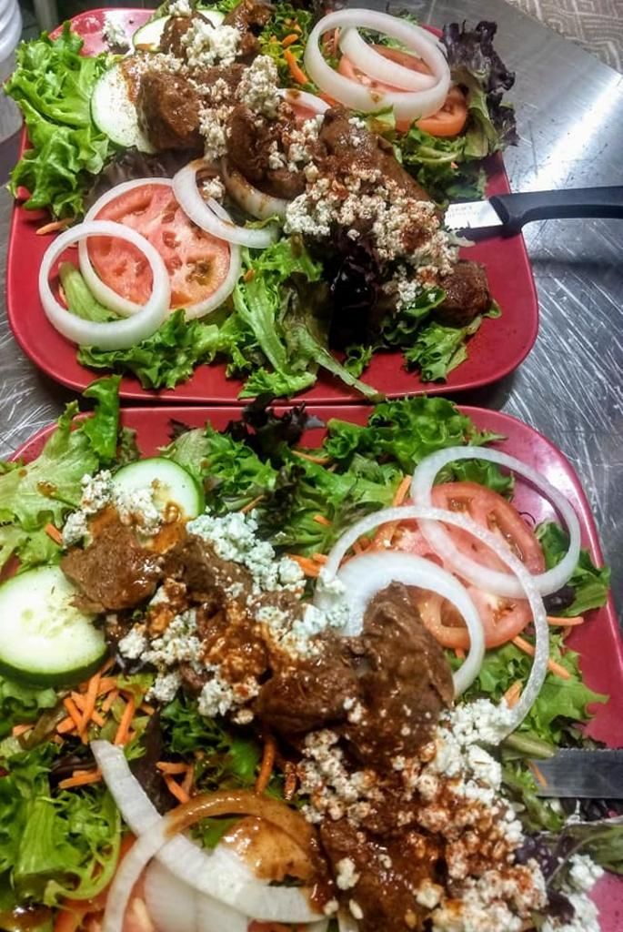 two plates of salad with meat and vegetables on them