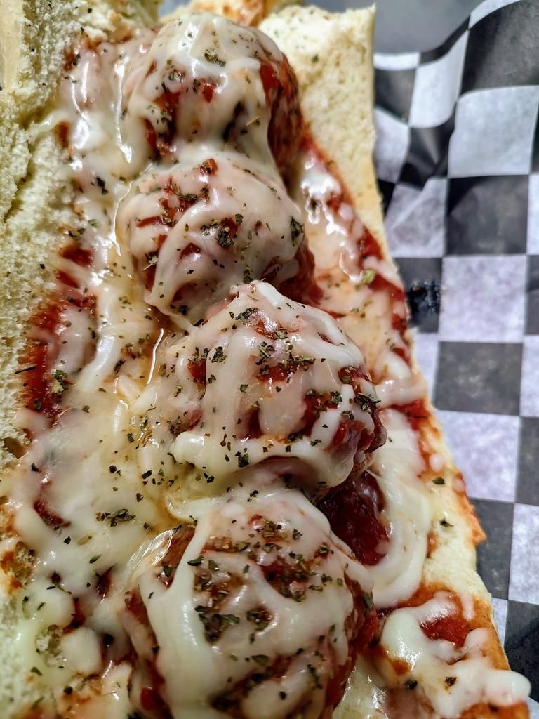 a sandwich with meatballs and cheese on a checkered napkin