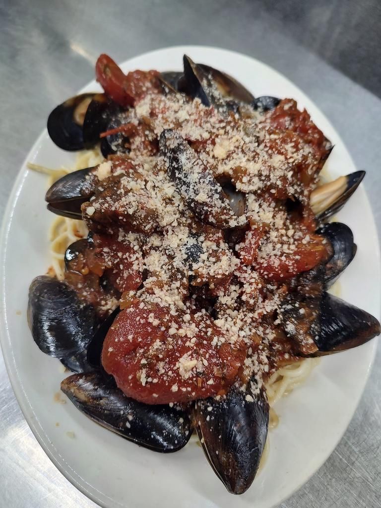 a white plate topped with spaghetti mussels and sauce