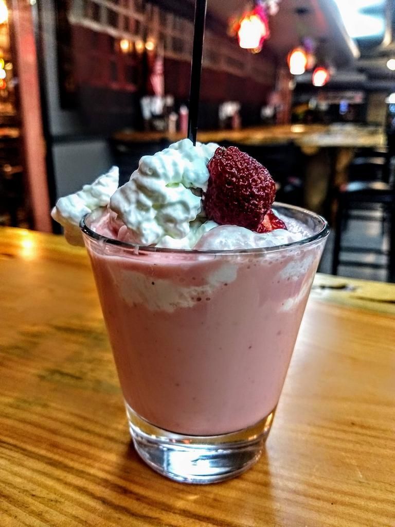 a pink drink with whipped cream and strawberries on top