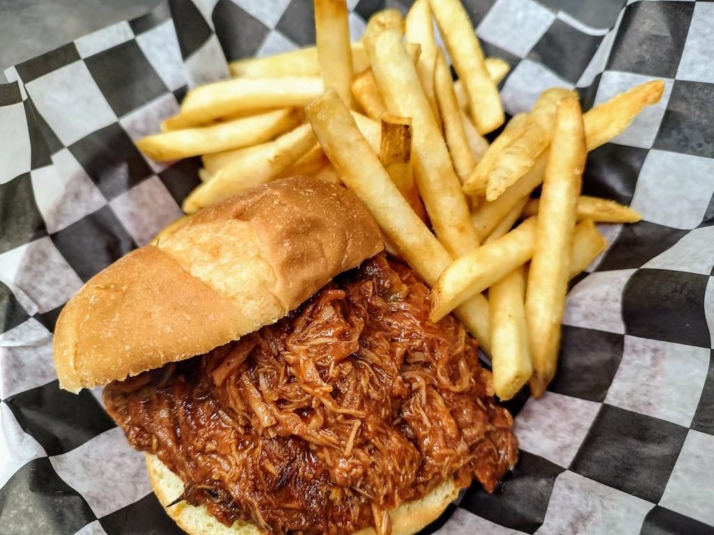 a pulled pork sandwich and french fries in a basket