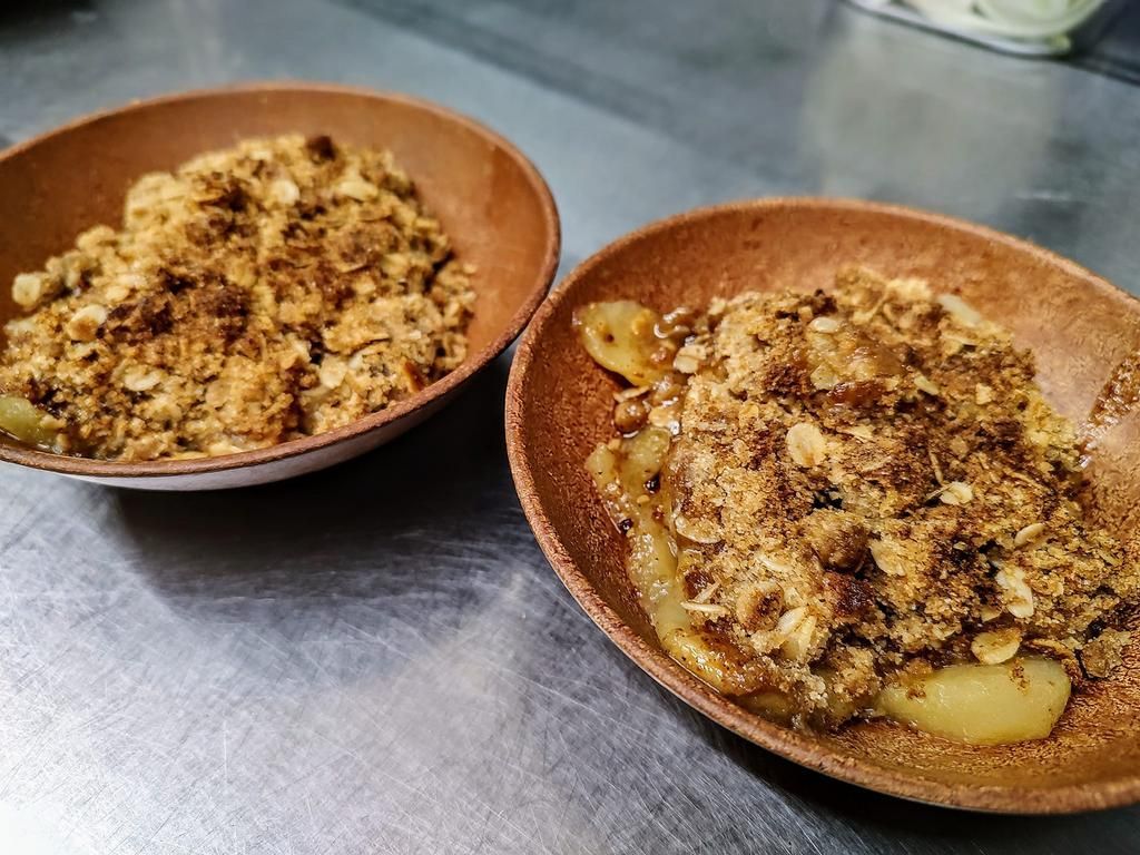 two bowls of apple crumble are on a table