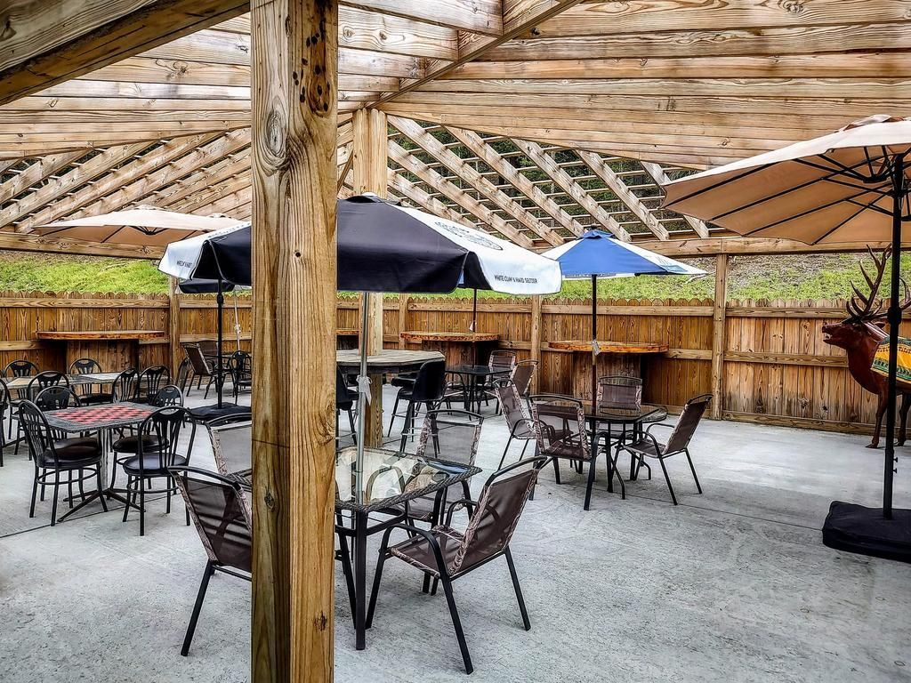 tables and chairs under a pergola with umbrellas that say busch