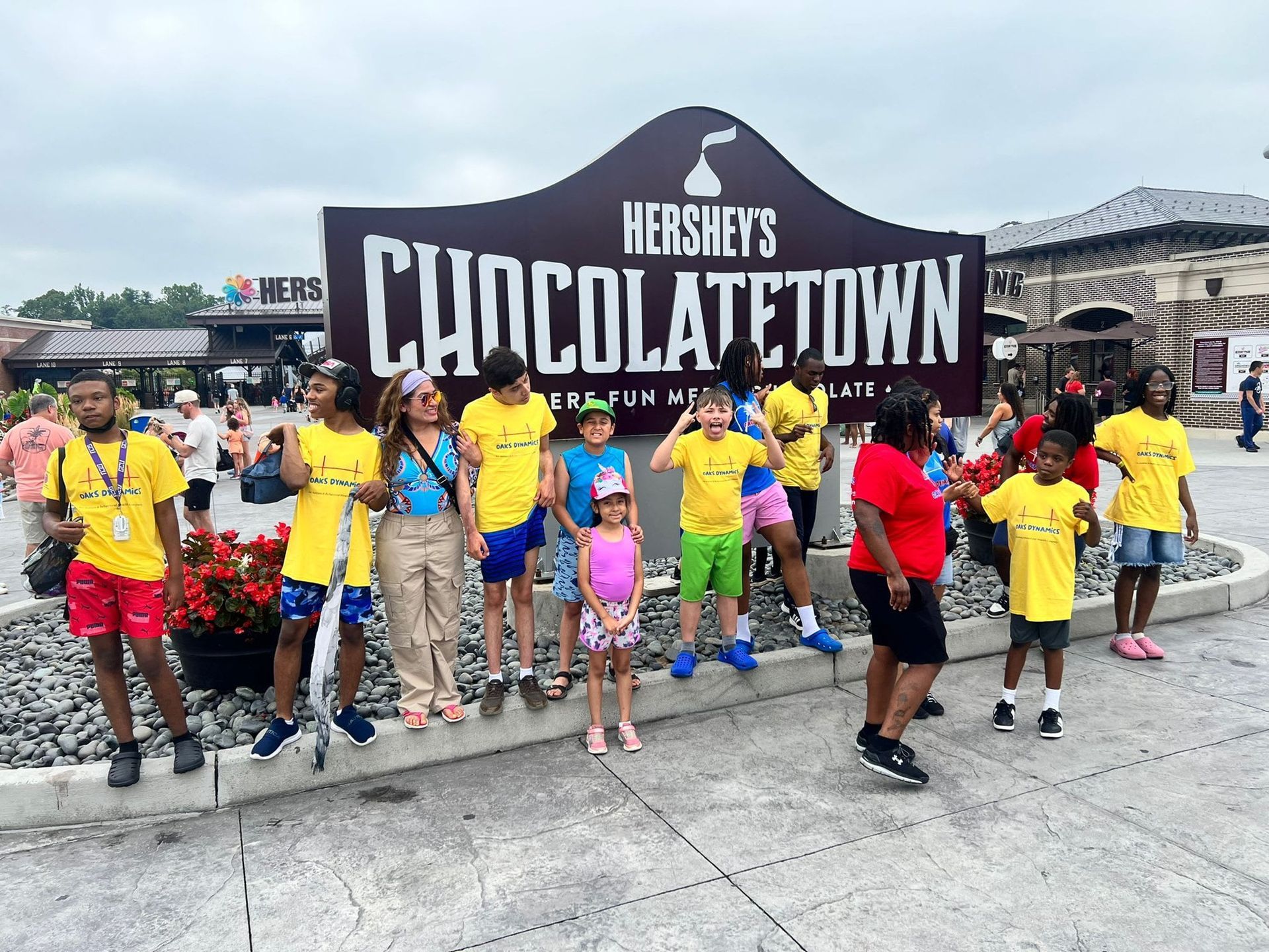 Group of people in yellow shirts pose in front of Hershey's CHOCOLATE TOWN sign.