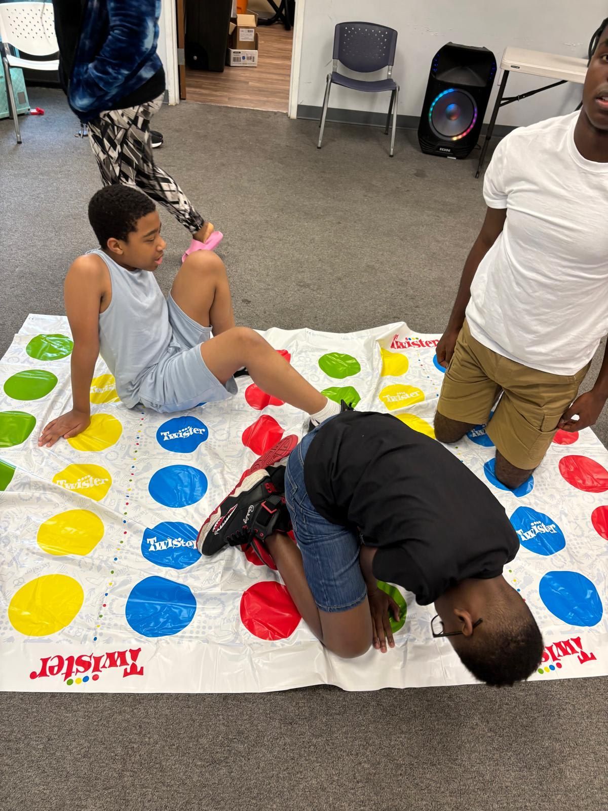 People playing Twister on a game mat indoors. 