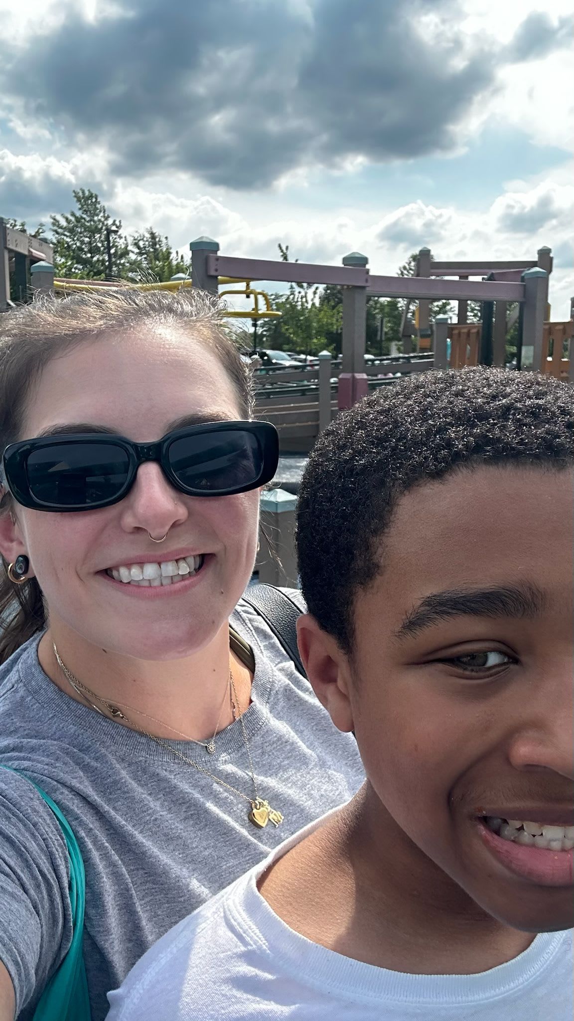 Woman in sunglasses smiles with a boy wearing braces.