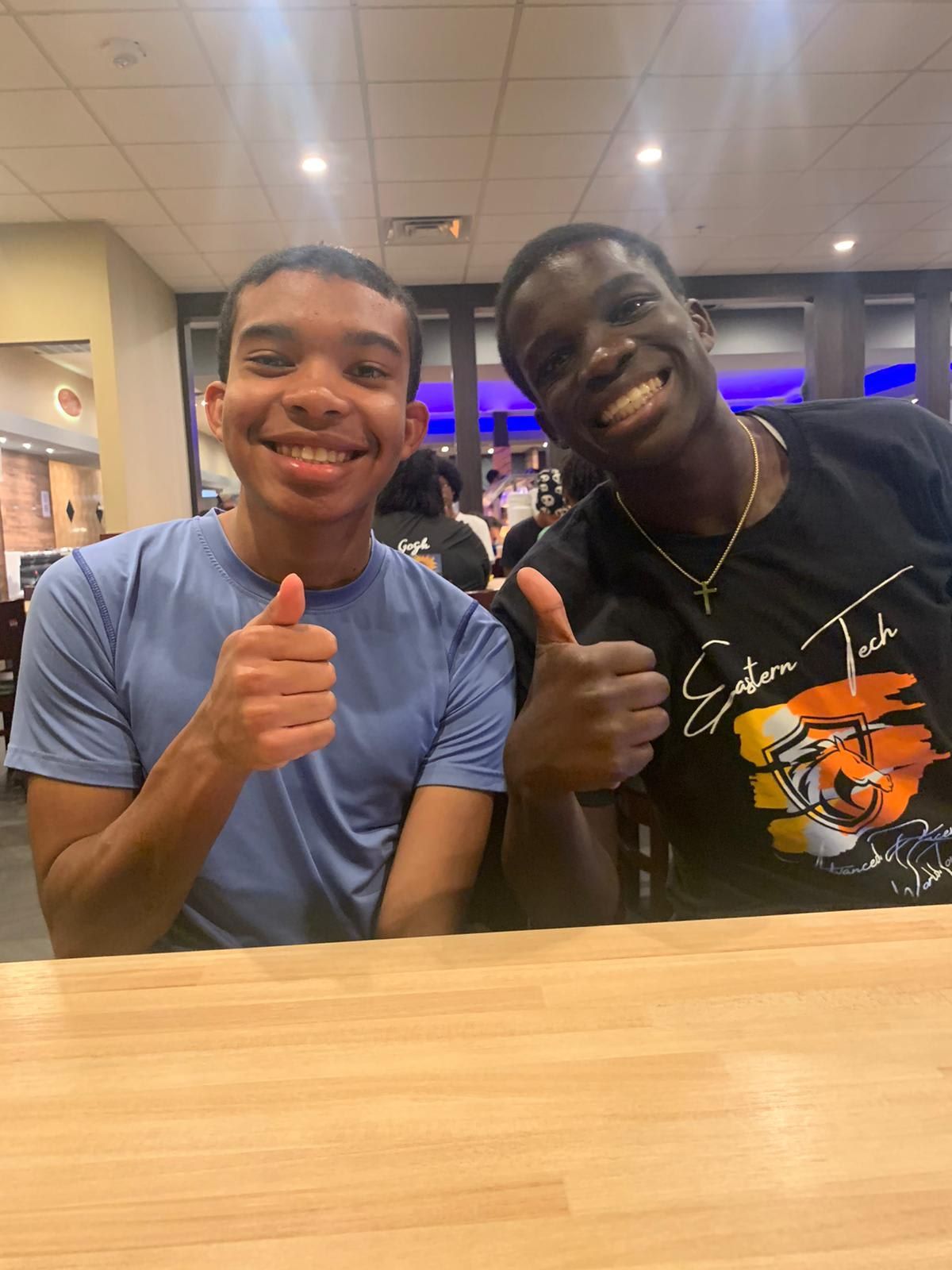 Two smiling people with thumbs up at a restaurant. 