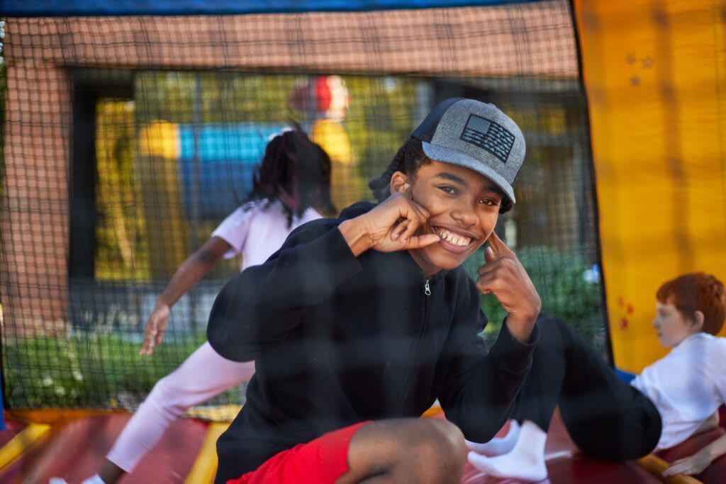 Person smiling in front of a bouncy castle, making a face. 