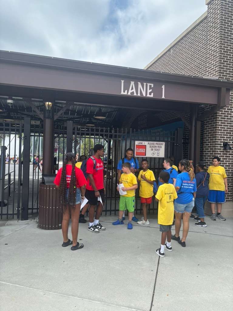 People in colorful shirts outside a building labeled 