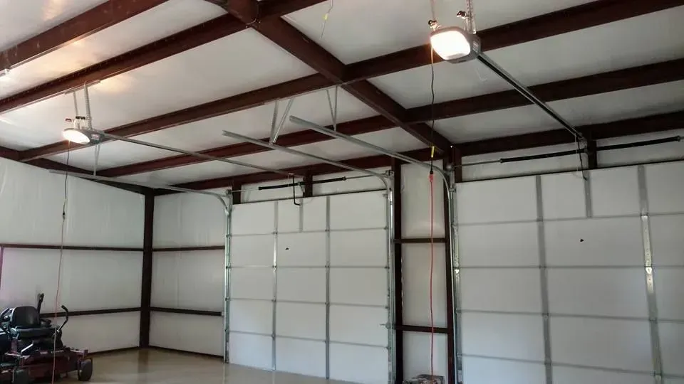 Empty garage interior with unfinished drywall, concrete floor, and sunlight near the opening
