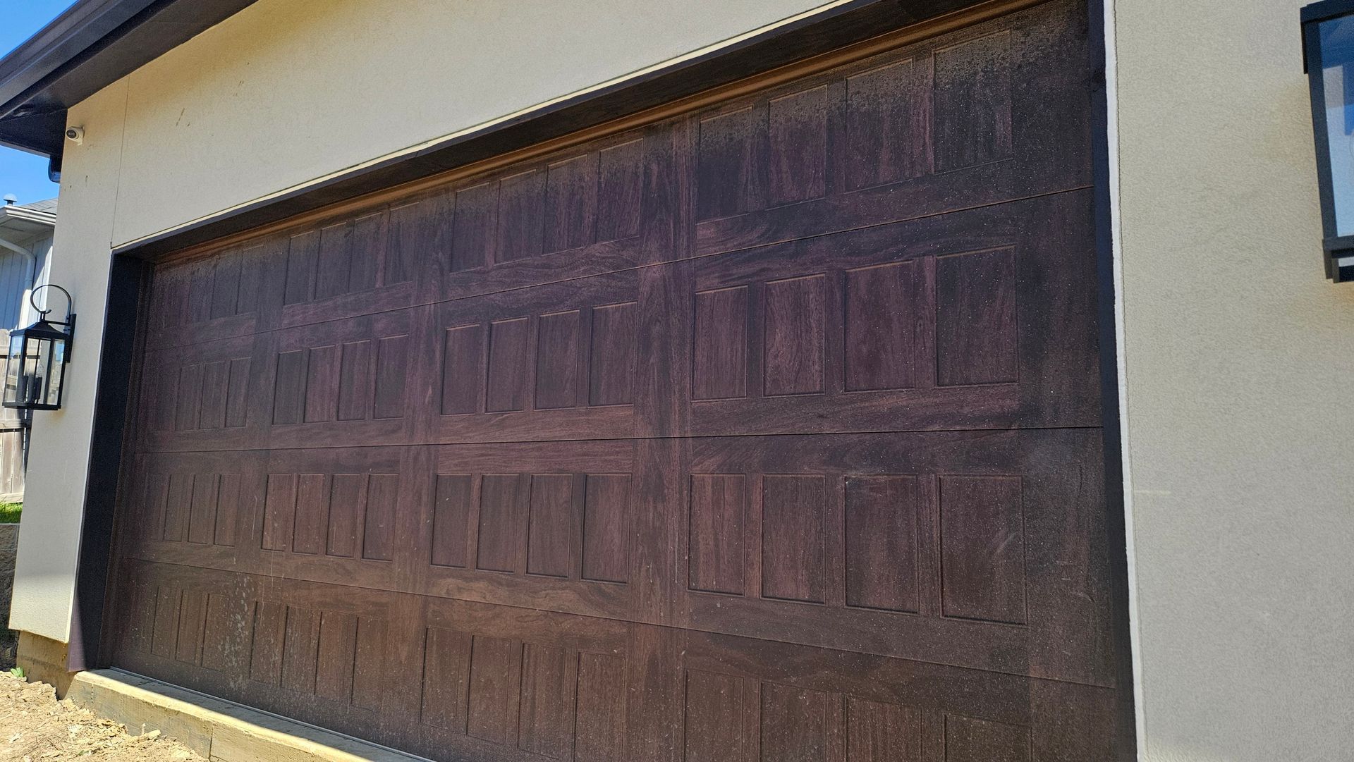 Closed dark wooden garage door on a beige house exterior