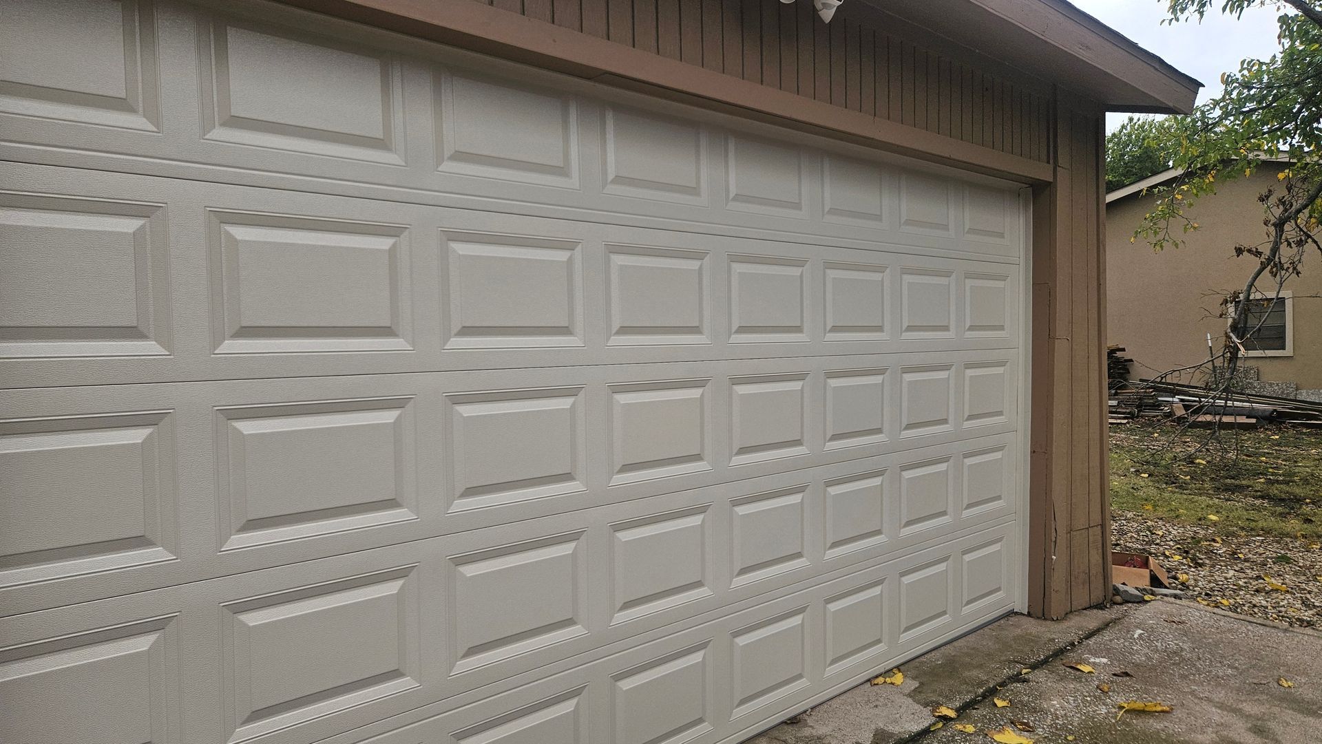 White garage door on a house exterior with beige trim and a driveway beside it