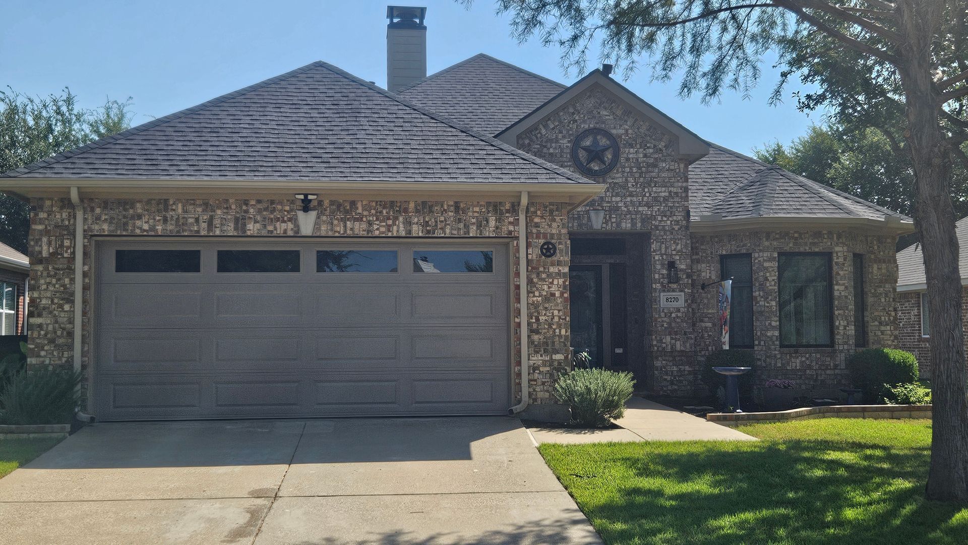 Brick house with a two-car garage, arched entryway, and front lawn in daylight