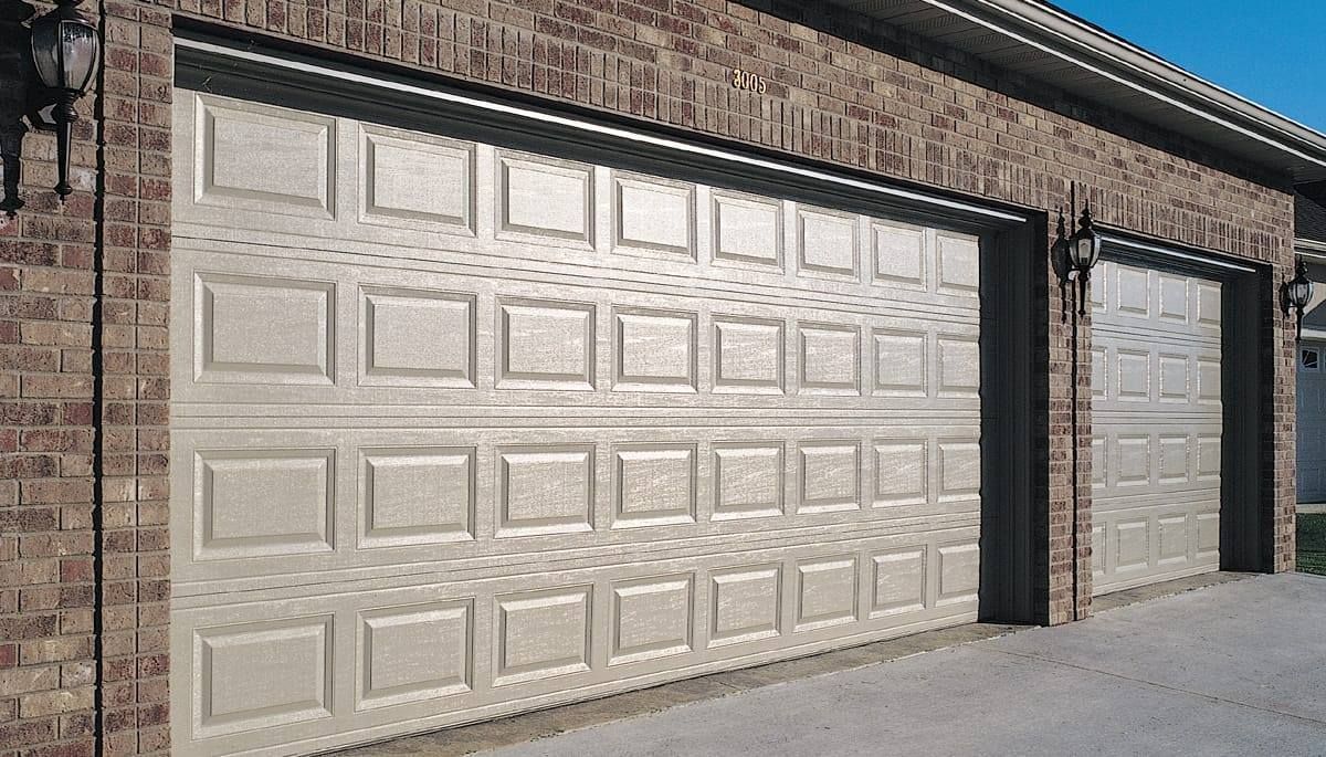 Large white garage door in a brick building with a small side door on the right.
