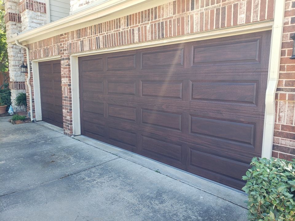 Brown double garage door on a brick house with a concrete driveway