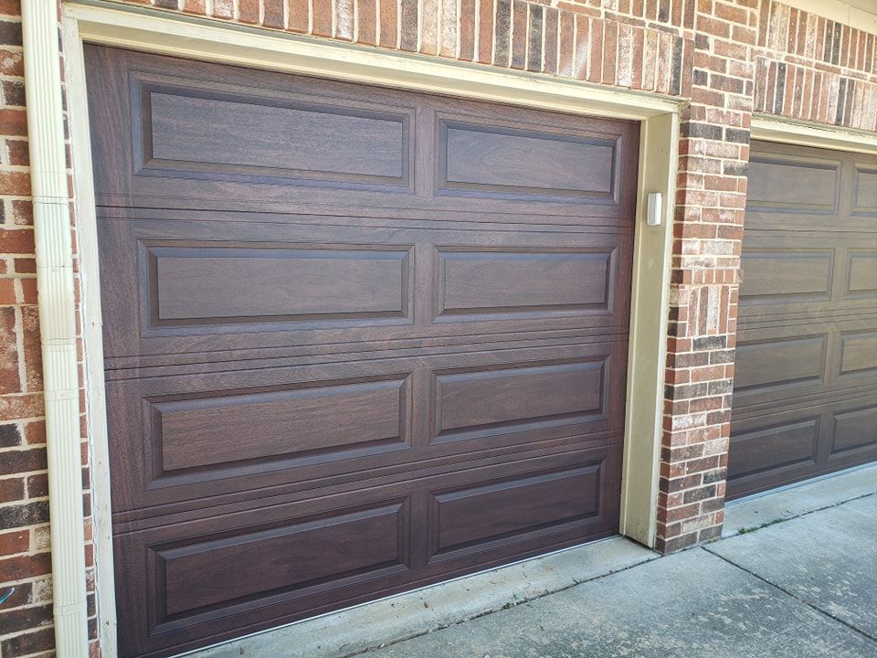 Brown paneled garage doors on a brick house driveway