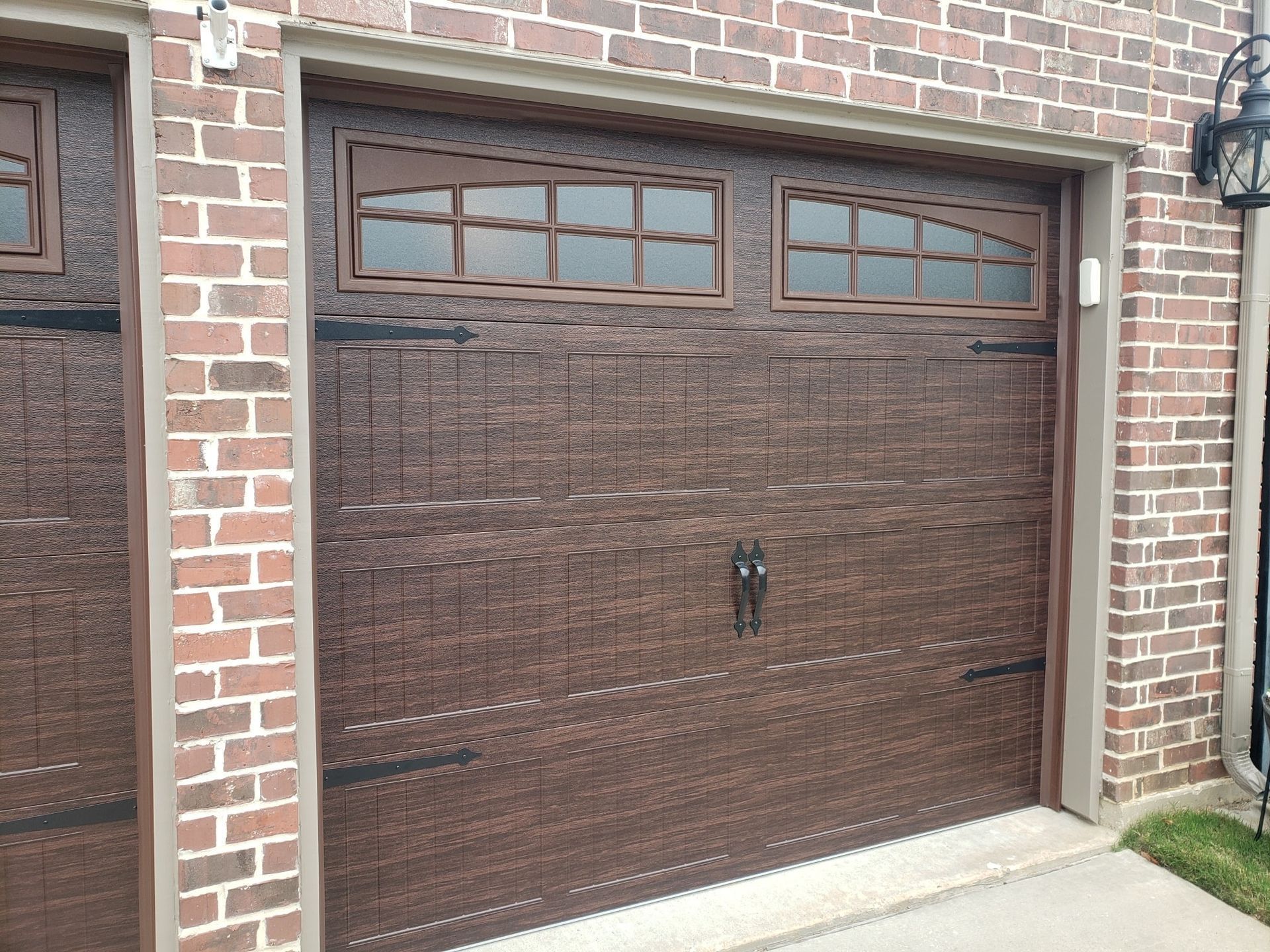 Brown garage door with small windows set in a brick house exterior