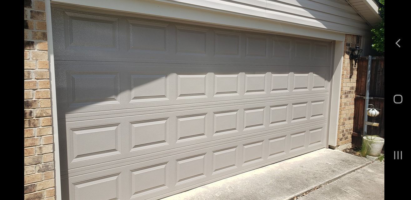White garage door with decorative panels on a house exterior, viewed from the driveway.