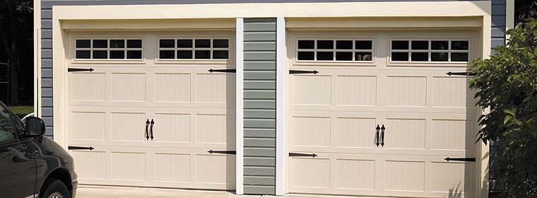 Two white garage doors with small windows above, front view of a house.