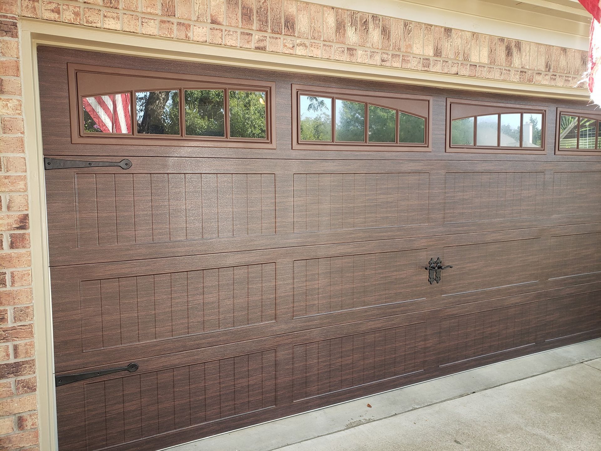 Brown garage door with small windows in a brick house facade