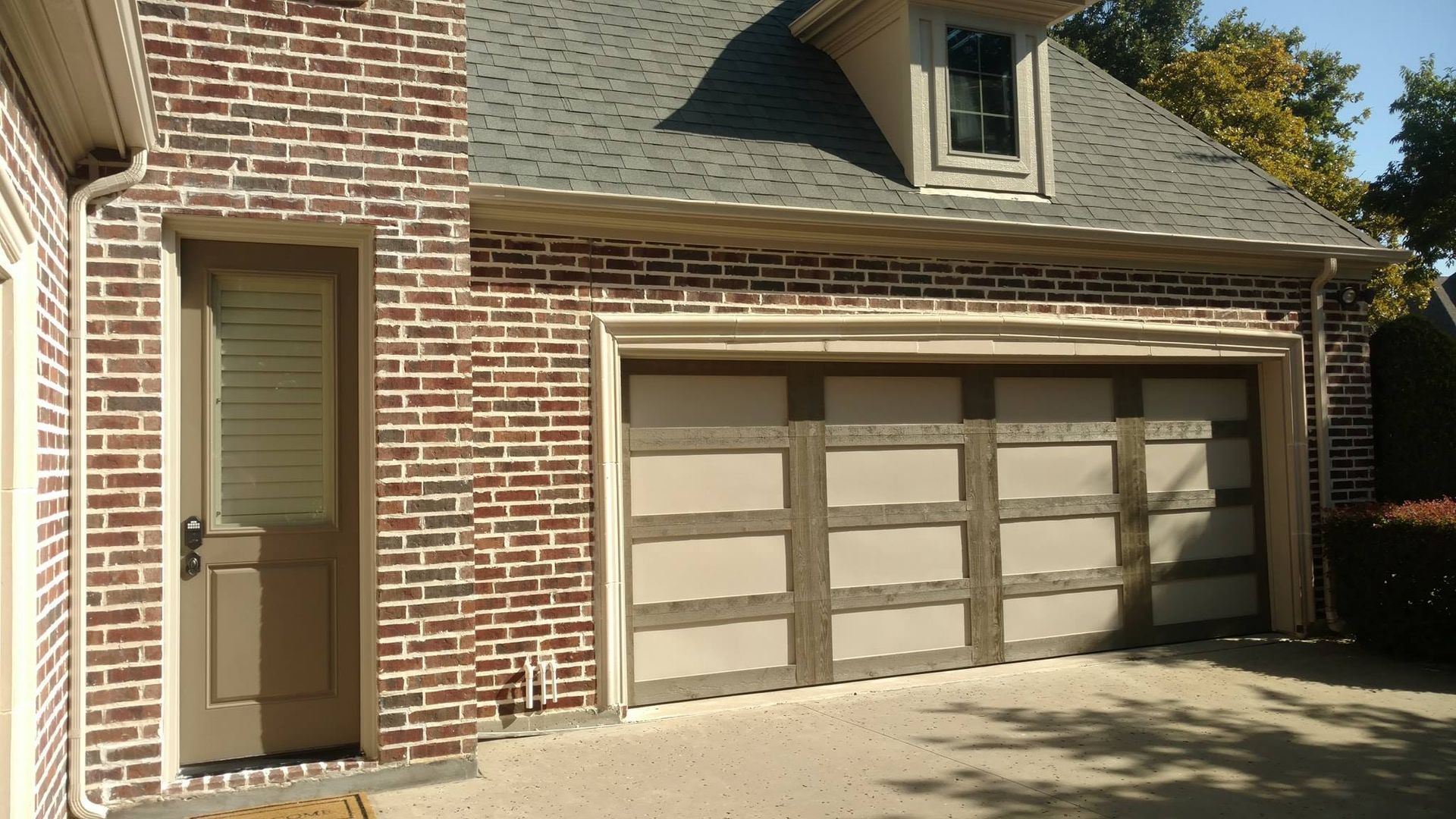 Brick house exterior with double garage doors and a narrow side entry door.