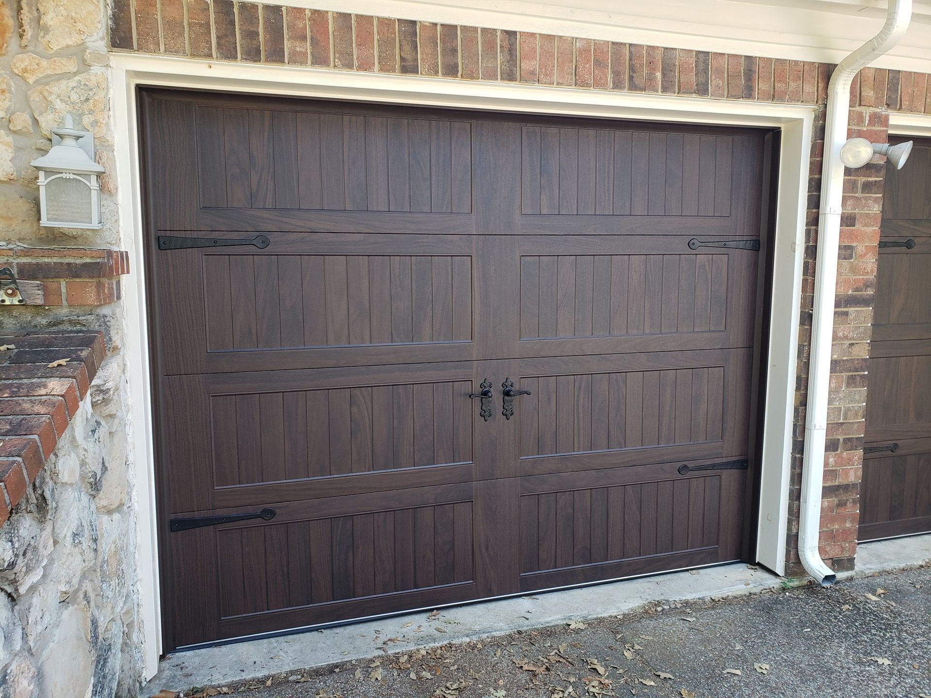 Brown double garage door on a brick house exterior