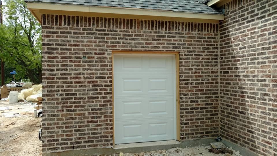 Brick exterior wall with a beige service door under a roof overhang.