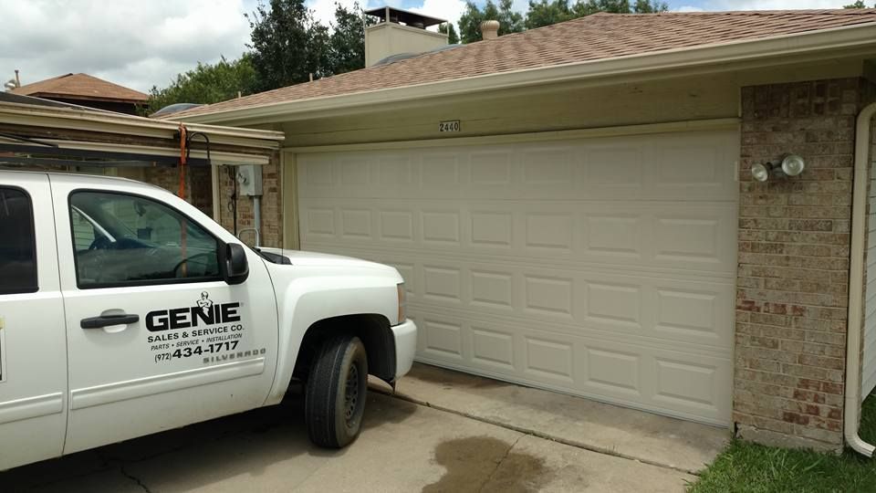White service truck parked in front of a beige two-car garage with stone siding and a tiled roof