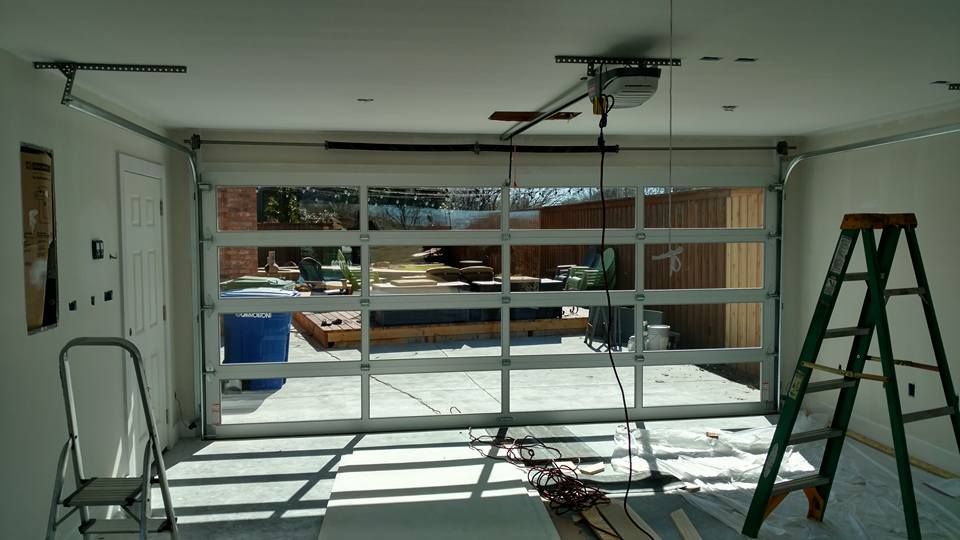 Garage under construction with open door, ladder, tools, and bright sunlight streaming in