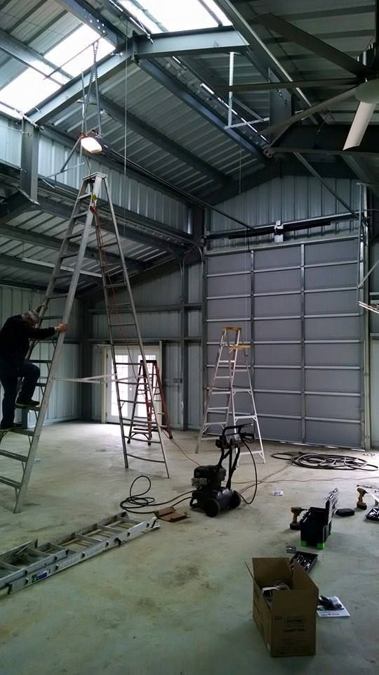 Industrial workshop interior with ladders, tools, and a person working near the left wall