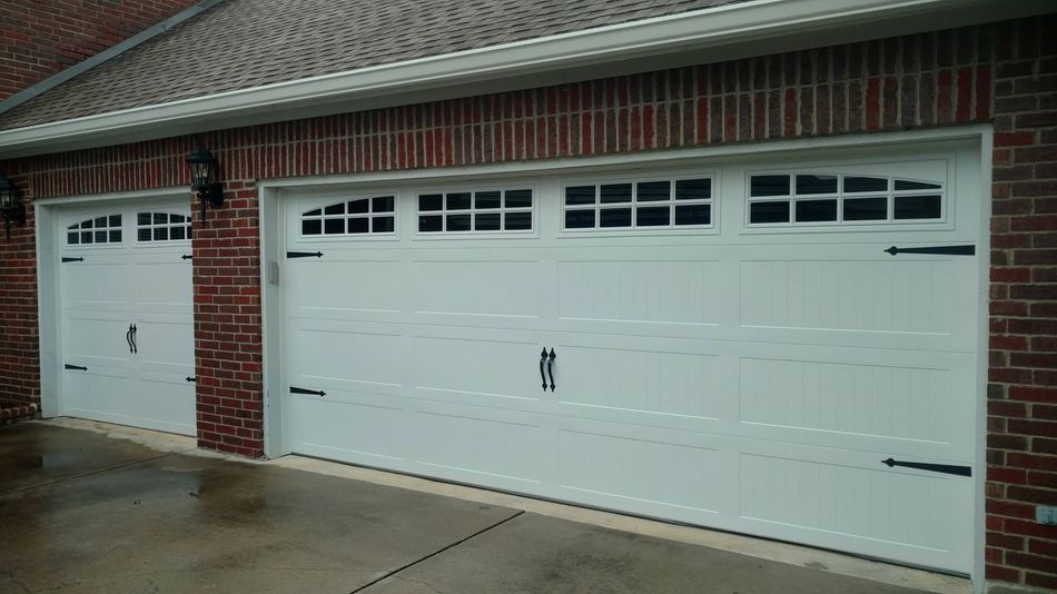 White double garage door on a brick house with a smaller side door.