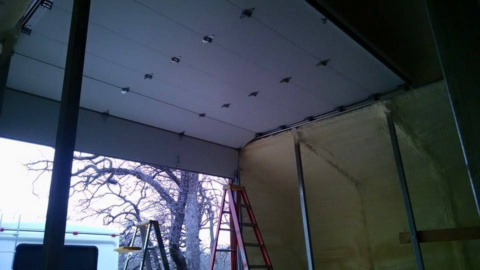 Partially finished room with a drop ceiling, red ladder, and exposed wall by a large window