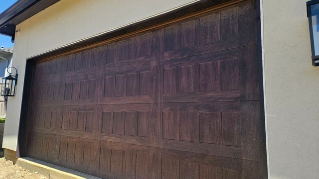 Large dark wooden garage door set in a beige stucco exterior wall.