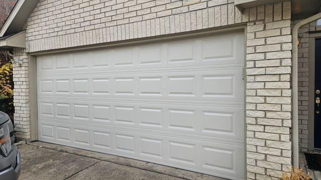 White double garage door on a brick house with a concrete driveway nearby