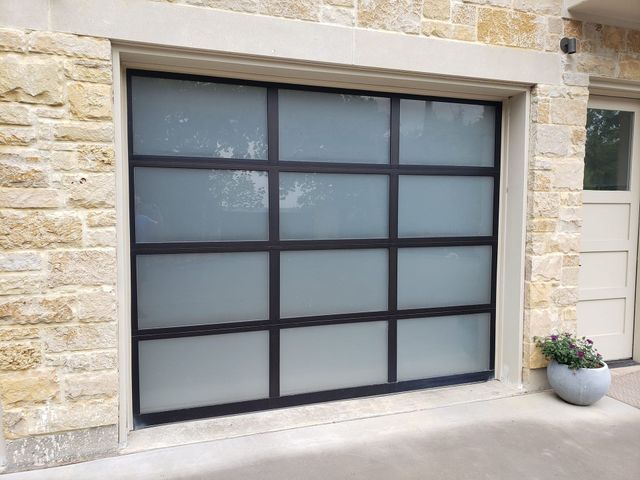 Frosted glass garage door set in a stone exterior wall with a small potted plant beside it