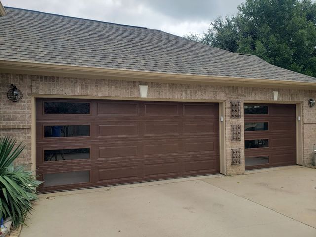 Two-car garage with brown doors on a beige brick house and concrete driveway