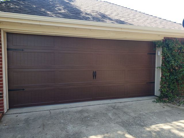 Closed brown garage door on a house with a concrete driveway and white trim