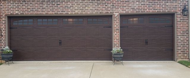 Two brown garage doors on a brick house with a concrete driveway