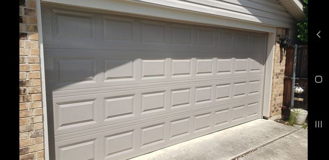 White garage door on a brick house, partially shaded by sunlight