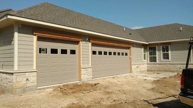 New beige house exterior with two attached garages and a dirt front yard