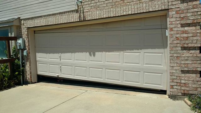 White garage door on a brick house with a driveway in front