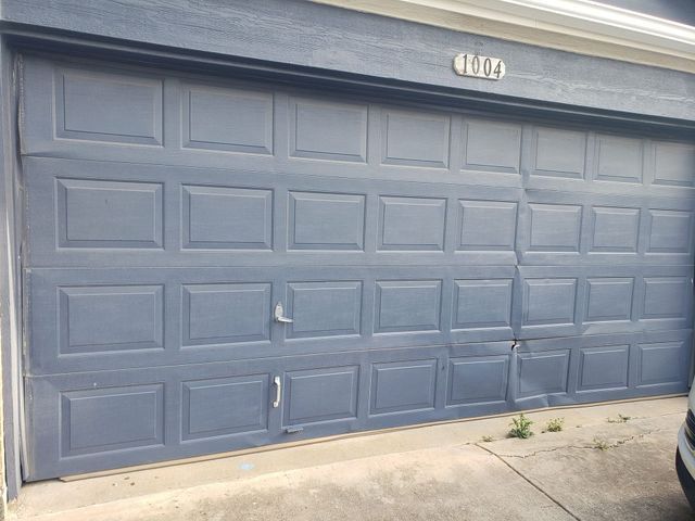 Blue paneled garage door on a concrete driveway, with house number 1007 above it.
