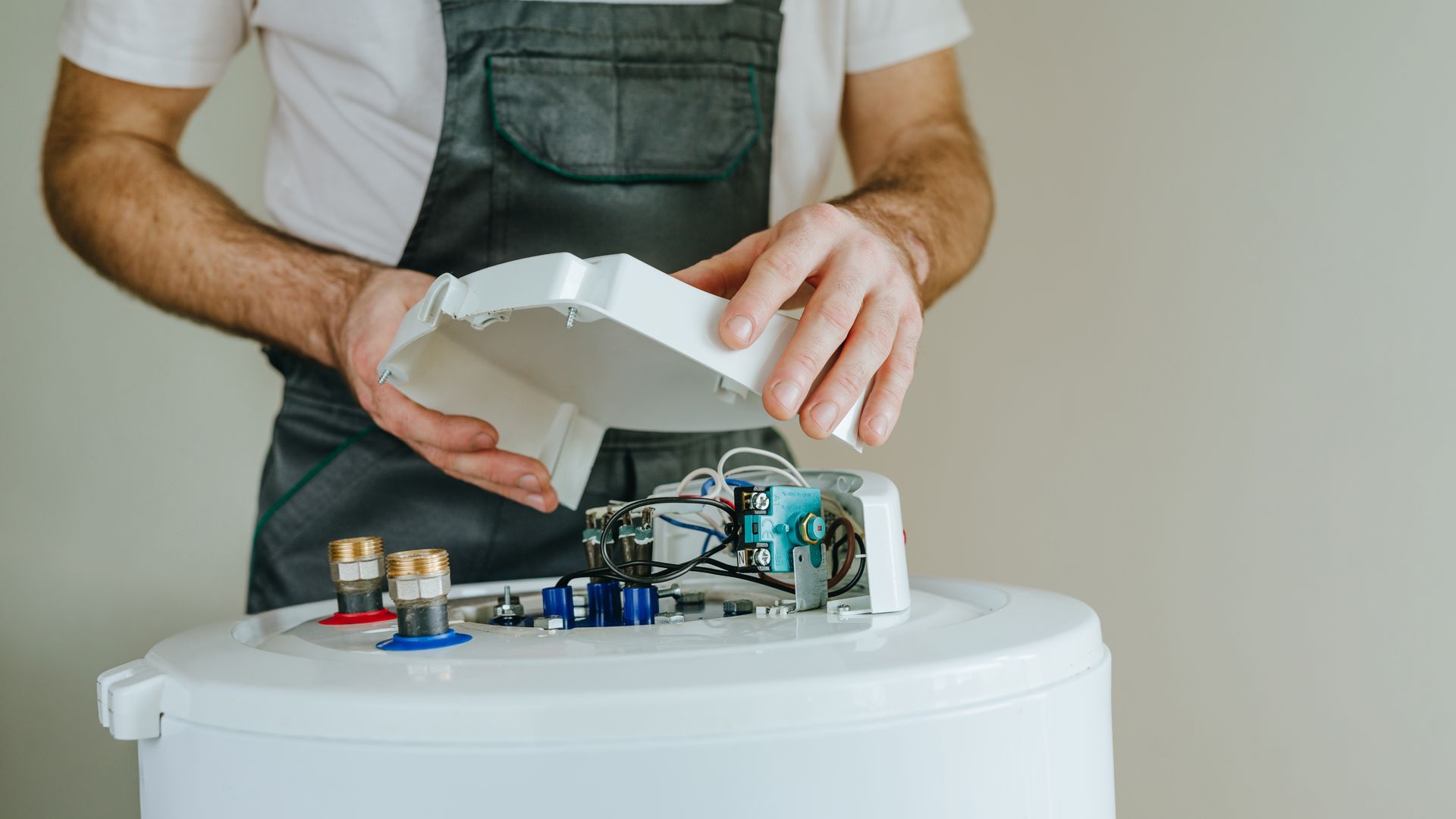 Person opening a white appliance to reveal tangled wiring and electronics on a table