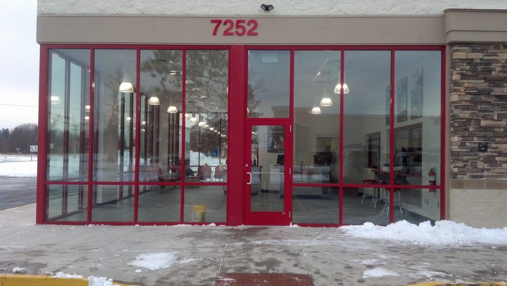 Red-framed glass storefront with red door, address