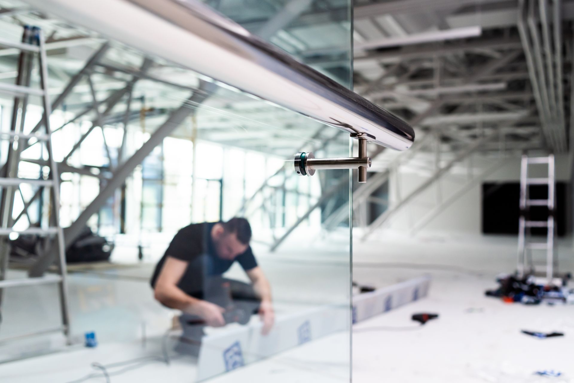 Worker installs modern glass partitions using robust hardware from a professional glass shop.