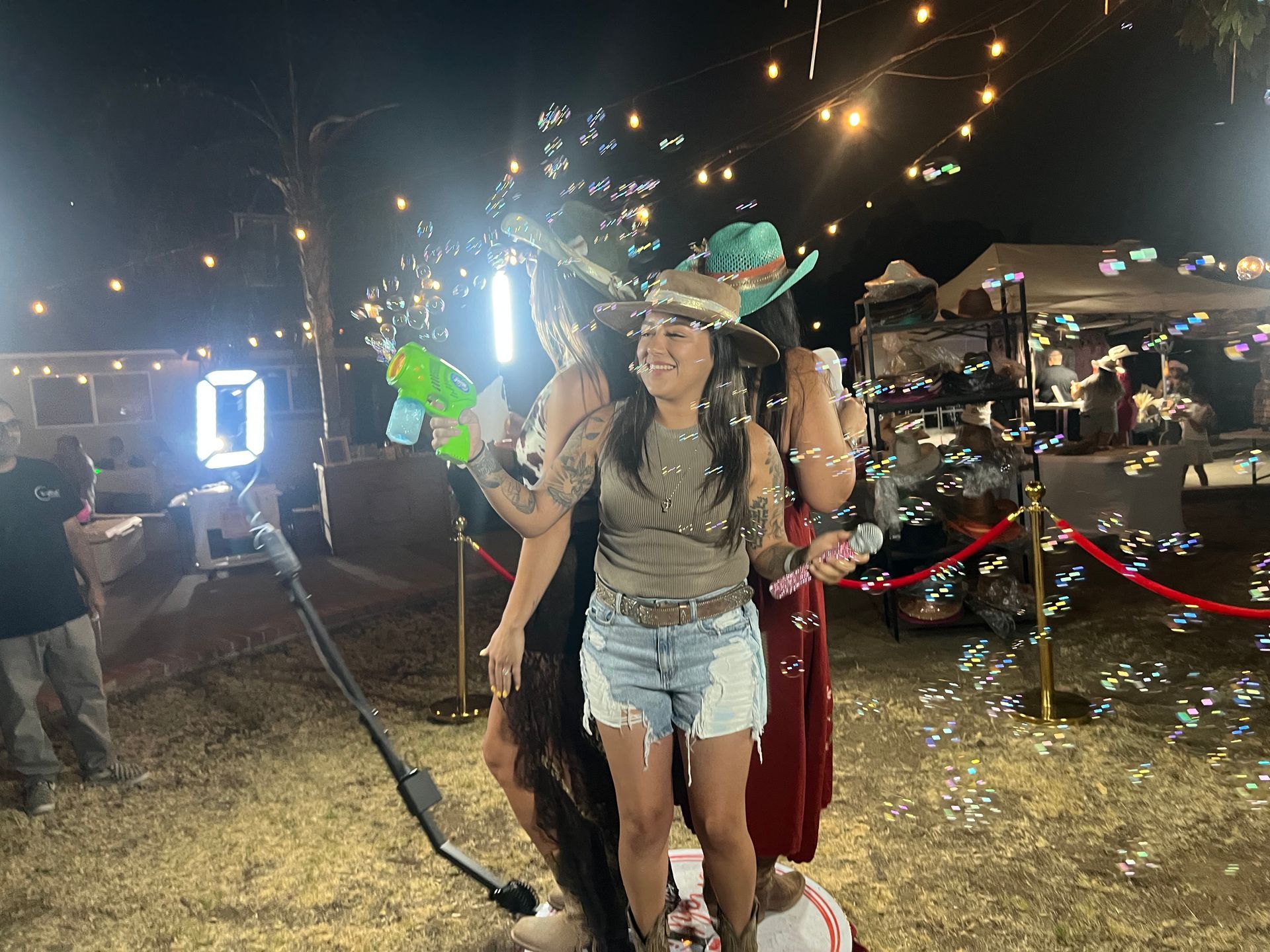 Guests enjoying a 360 Photo Booth with bubbles and props at an outdoor event