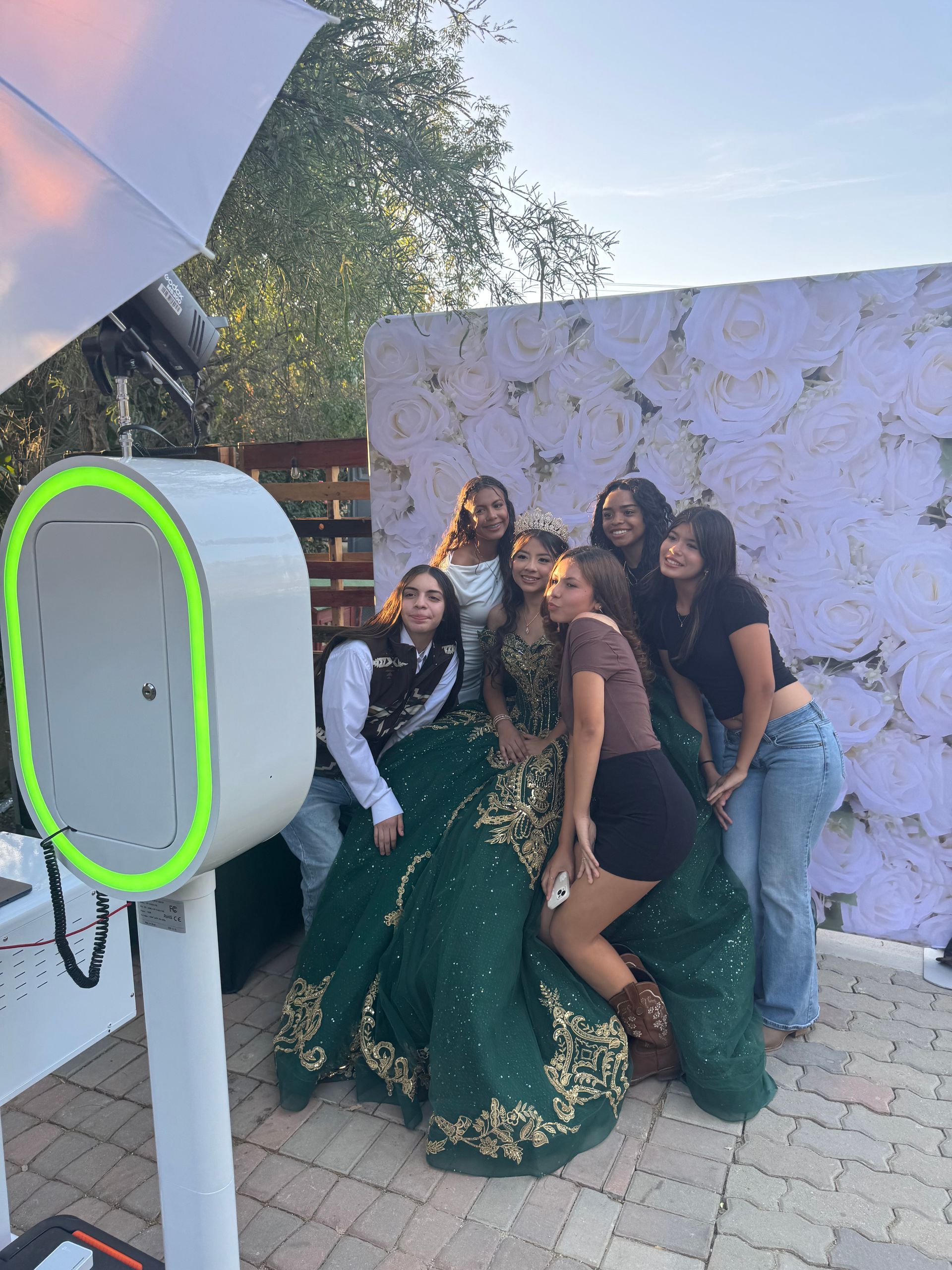 Guests enjoying Lily’s Quinceañera photo booth with a white rose backdrop in Perris, CA