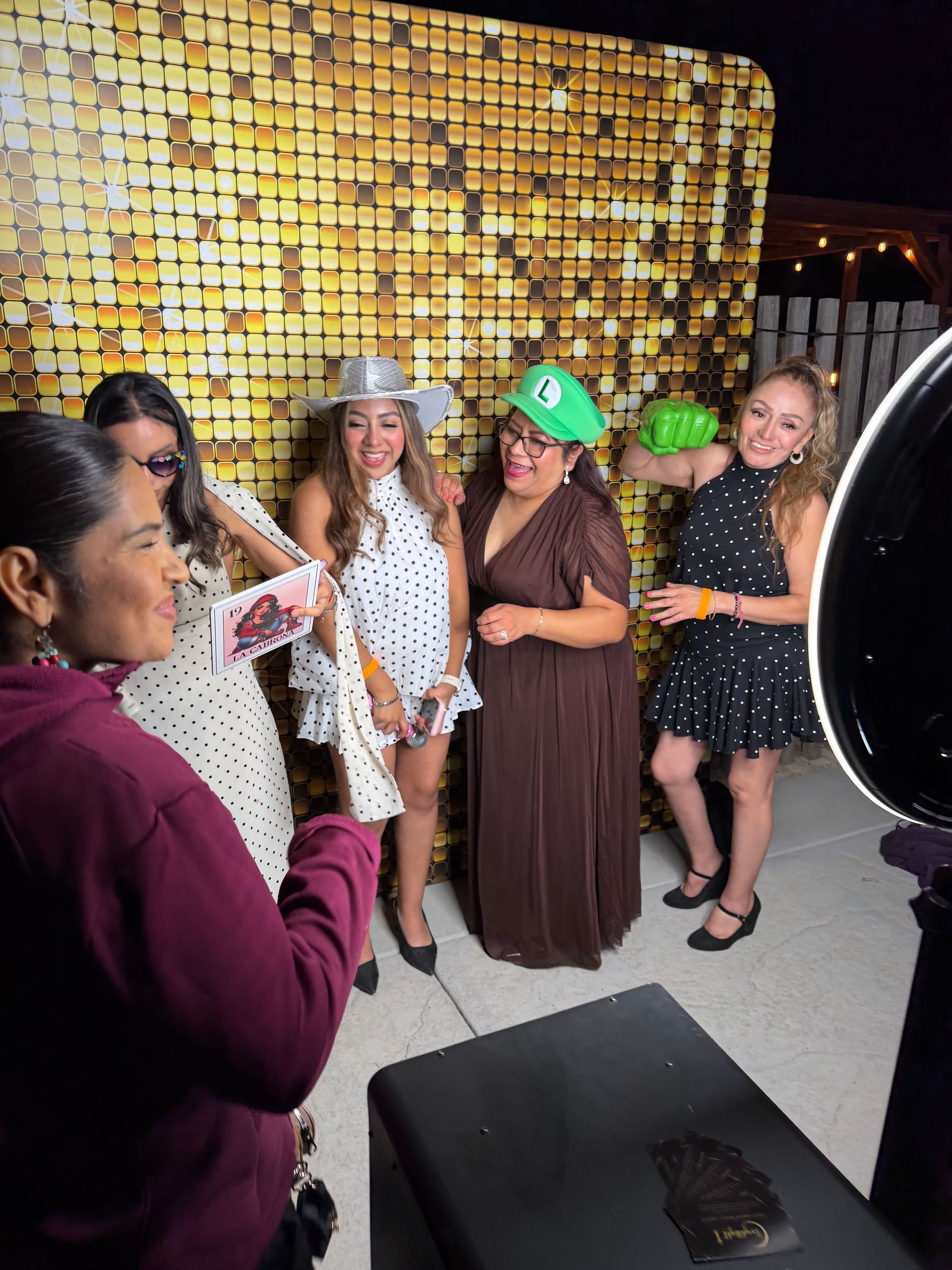 Guests having fun with photo booth props and a gold shimmer backdrop at Isabella’s Quinceañera in Perris, CA.