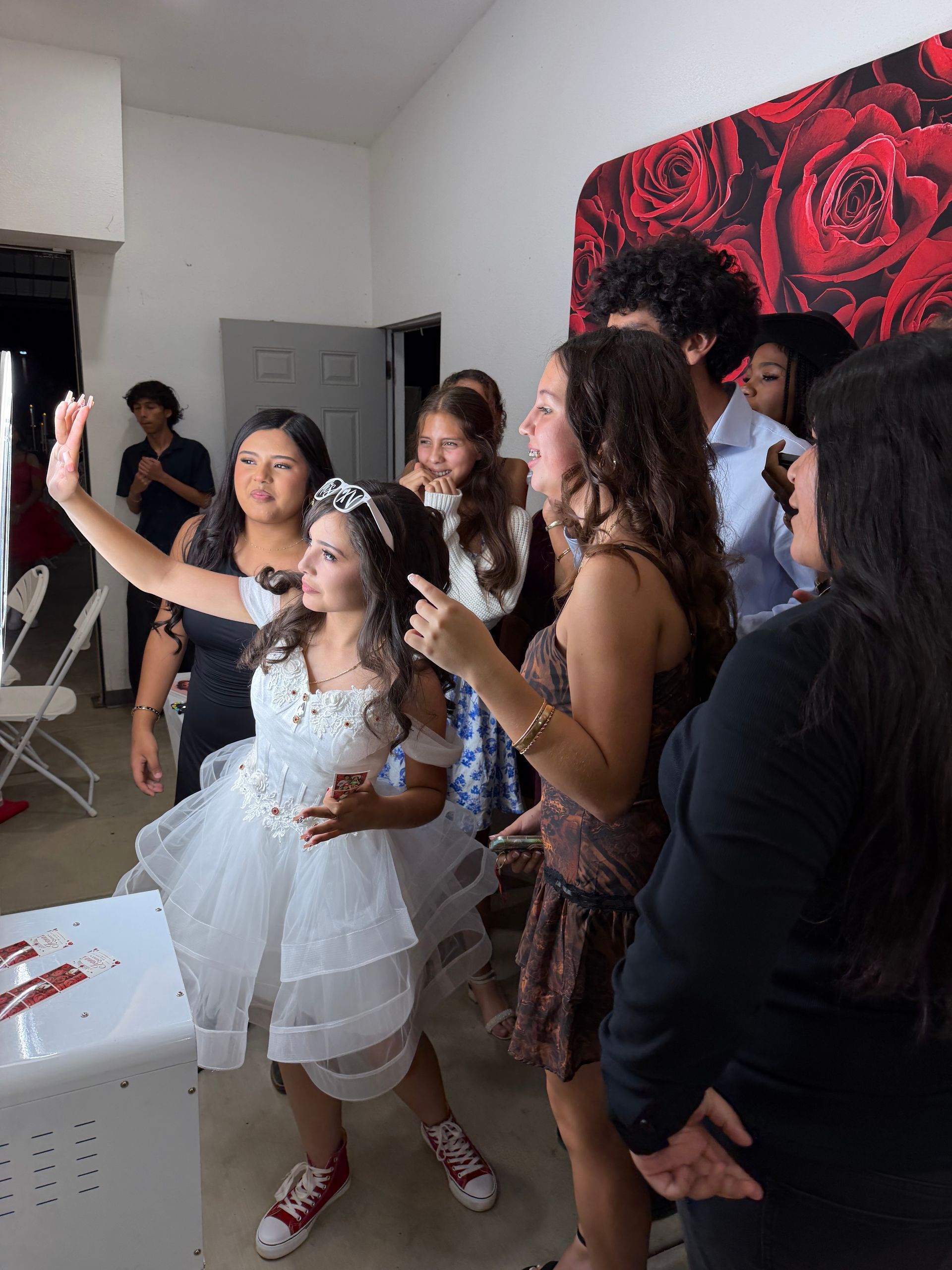 Guests enjoying Ivana’s Quinceañera photo booth with a red rose backdrop at Rancho Salgado in Perris